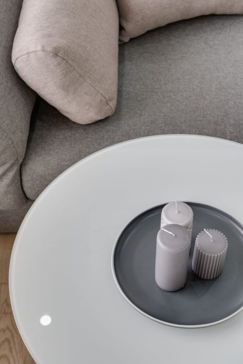Popielata sofa z beżowymi poduszkami i okrągłym stolikiem w jasnym salonie