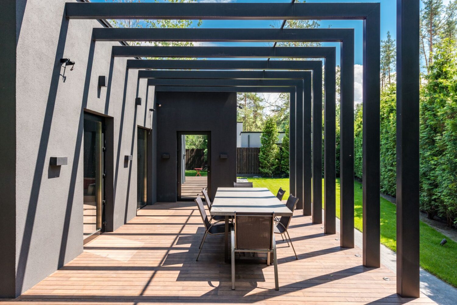 Nowoczesna pergola aluminiowa nad tarasem ze stołem i krzesłami