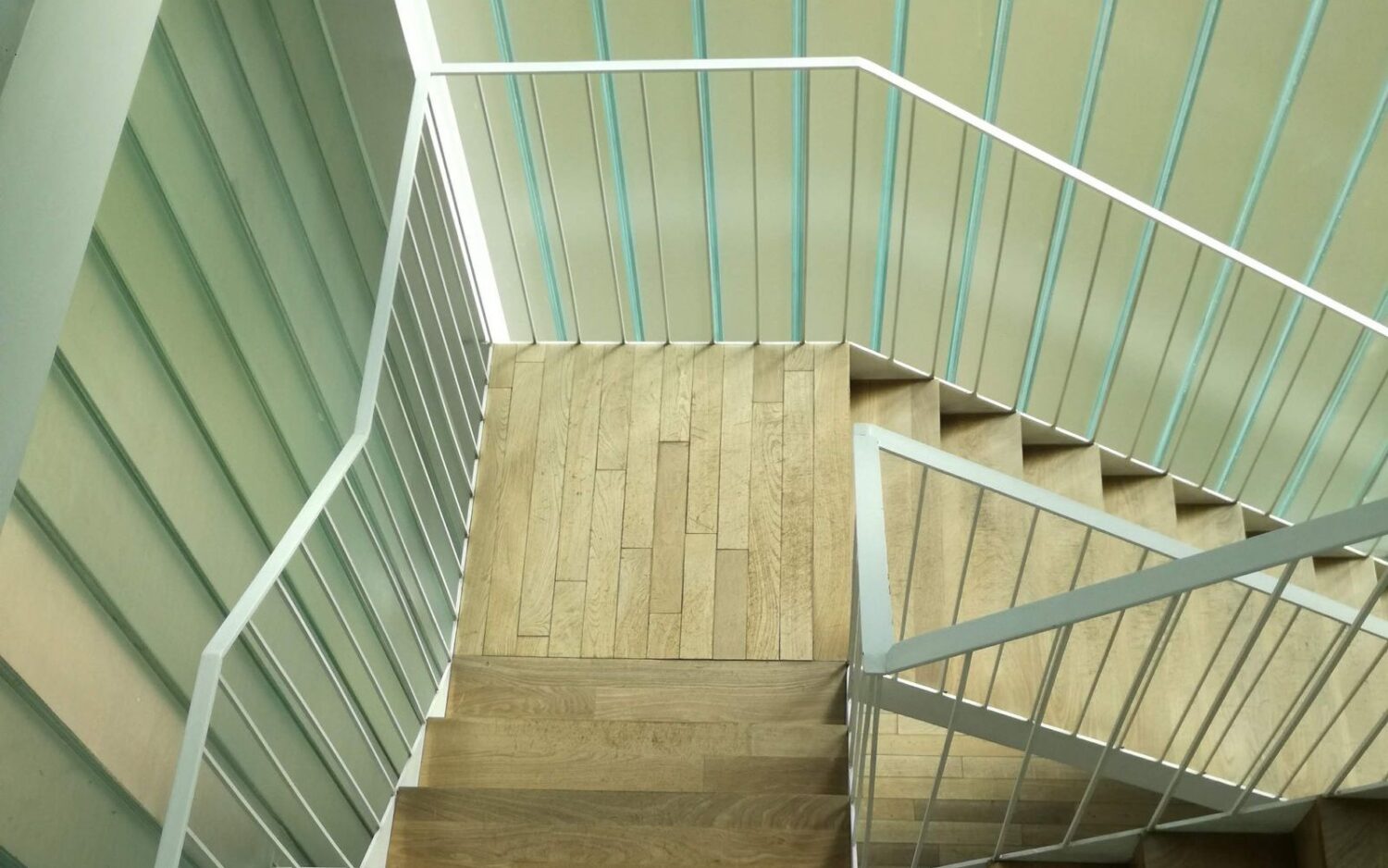 Drewniane schody z białą balustradą o pionowych szczeblinach widziane z góry